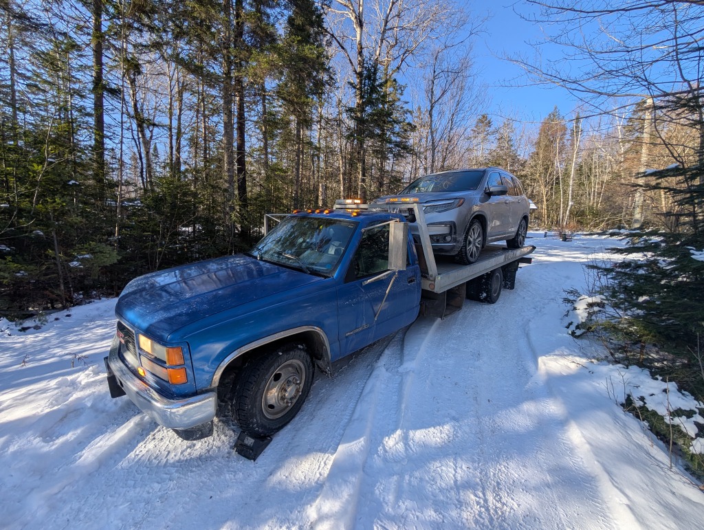 Grey Honda Pilot SUV recovery in snowy woods